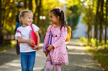 Two young girls wearing backpacks and carrying school books - Teacher recruitment